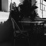 An outdoor cafe table and chairs in shadow.