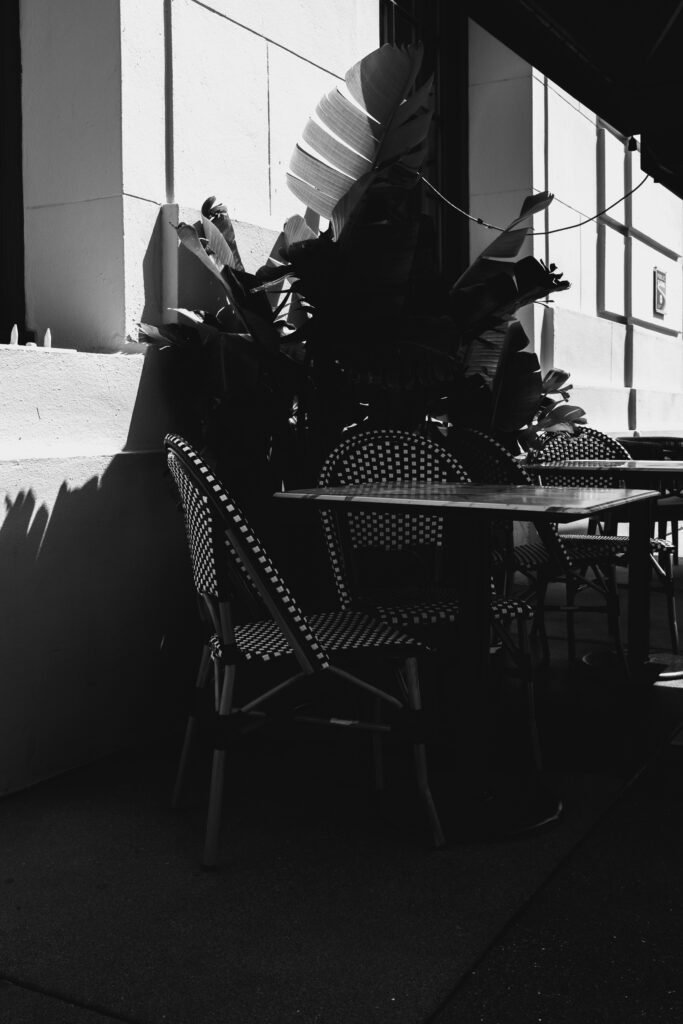 An outdoor cafe table and chairs in shadow.